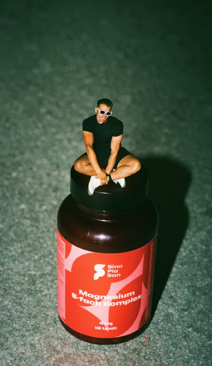 Miniaturfigur sitzt auf einer Dose SinoPlaSan Magnesium
